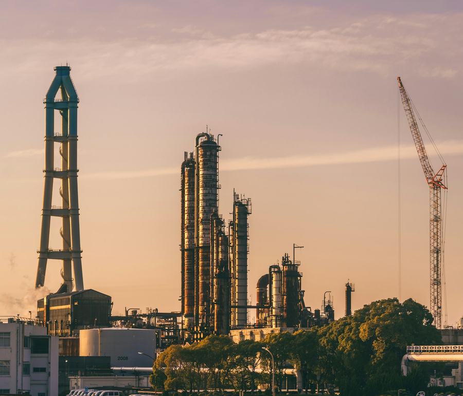 Refinery towers and a mobile crane at sunset